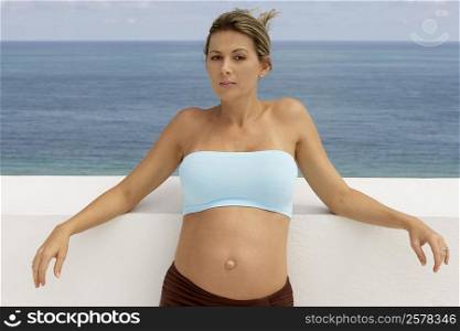 Portrait of a pregnant woman leaning against the wall