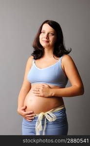 Portrait of a pregnant woman touching her belly with hands