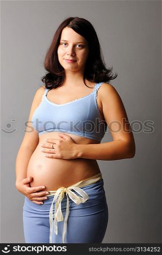 Portrait of a pregnant woman touching her belly with hands