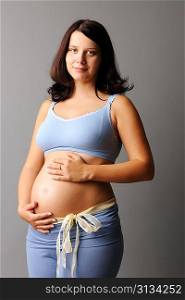 Portrait of a pregnant woman touching her belly with hands