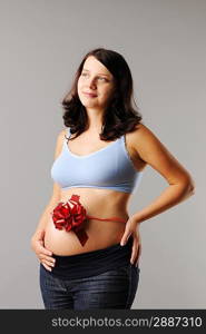 Portrait of a pregnant woman with wrapping bow on her her belly
