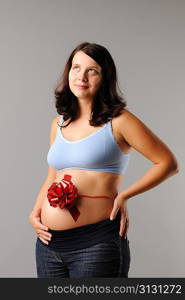 Portrait of a pregnant woman with wrapping bow on her her belly