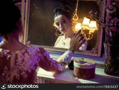 Portrait of a pretty, brunette countess touching an antique mirror