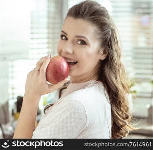 Portrait of a pretty lady biting a fresh apple