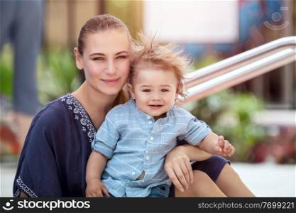 Portrait of a pretty mother with her precious little son with pleasure spending summer holidays on the beach resort, happy family life