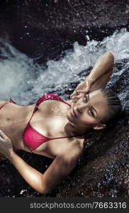 Portrait of a pretty relaxed woman taking a bath in the waterfalls