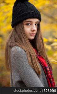 Portrait of a pretty teenage girl looking straight to camera with autumnal colours in the background