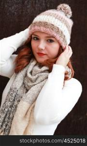 Portrait of a pretty teenage girl with redhair holding on to her hat