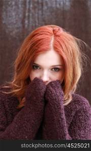 Portrait of a pretty teenage girl with redhaircovering her face with her hands