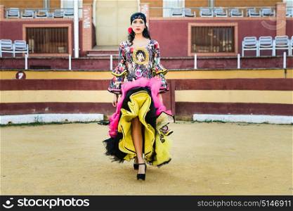 Portrait of a pretty woman, model of fashion, wearing a dress in a bullring. Spanish style