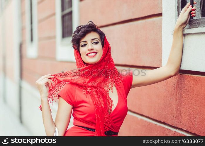 Portrait of a pretty woman, vintage style, in urban background, wearing a red dress