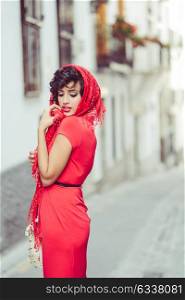 Portrait of a pretty woman, vintage style, in urban background, wearing a red dress