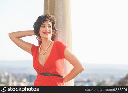 Portrait of a pretty woman, vintage style, in urban background, wearing a red dress