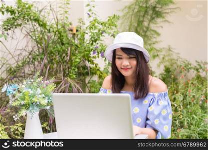 Portrait of a pretty young woman working on her computer on a terrace of her house