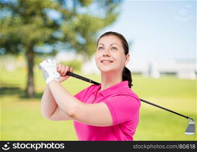 Portrait of a professional golfer in pink T-shirt with a golf club on a background of golf courses