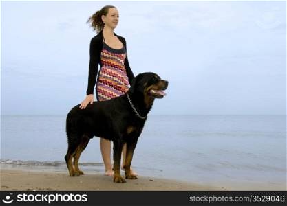 portrait of a purebred rottweiler and young woman on the beach