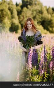 Portrait of a red-haired girl in a thicket of lupin.. A beautiful red-haired girl in a thicket of lupine 3283.