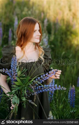 Portrait of a red-haired girl in a thicket of lupin.. A beautiful red-haired girl in a thicket of lupine 3286.