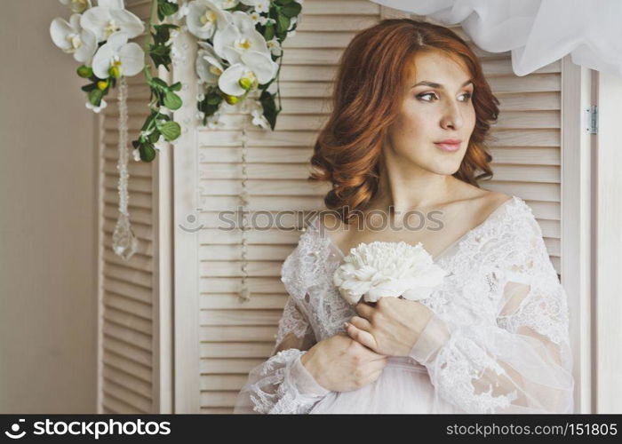 Portrait of a redhead girl in a gentle insolation.. Portrait of a girl on a background of white wooden blinds 6880.