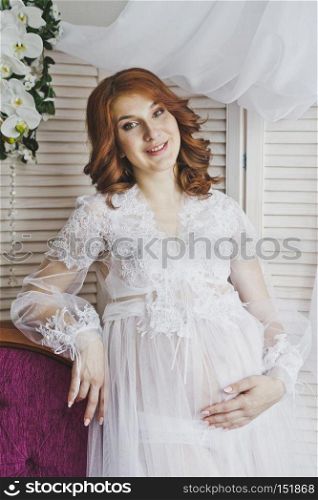 Portrait of a redhead girl in a transparent negligee.. Red-haired pregnant girl in a gentle environment 6828.