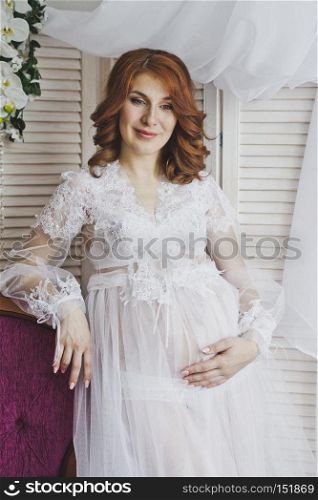 Portrait of a redhead girl in a transparent negligee.. Red-haired pregnant girl in a gentle environment 6829.