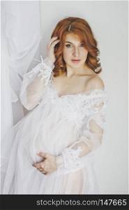 Portrait of a redhead pregnant girl in full growth.. Transparent womens dressing gown on the model 6849.