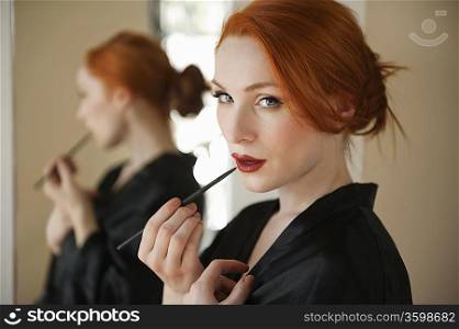 Portrait of a redheaded woman applying lip liner