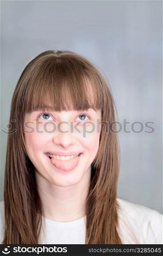 Portrait of a relaxed young woman smiling indoors with protruded tongue