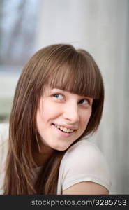 Portrait of a relaxed young woman smiling with hand on chin on sofa in living room