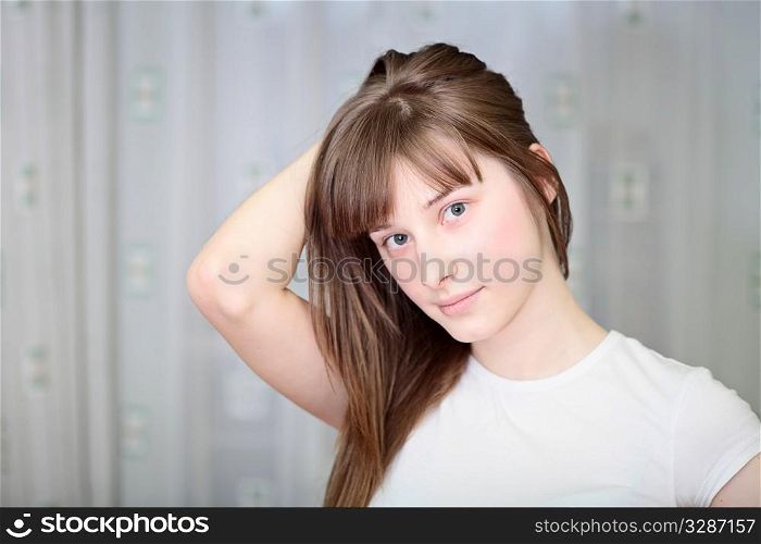Portrait of a relaxed young woman smiling with hand on chin on sofa in living room