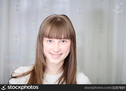 Portrait of a relaxed young woman smiling with hand on chin on sofa in living room