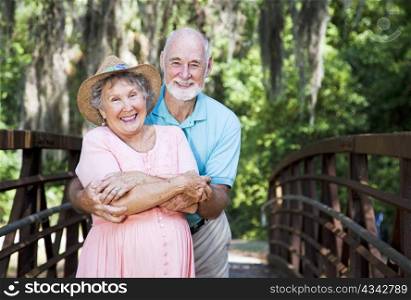 Portrait of a romantic senior couple on a bridge with Spanish Moss hanging overhead.