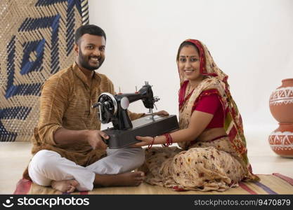 PORTRAIT OF A RURAL HUSBAND AND WIFE HOLDING SEWING MACHINE AND SMILING AT CAMERA