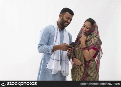 PORTRAIT OF A RURAL HUSBAND AND WIFE LOOKING AT MOBILE PHONE AND LAUGHING