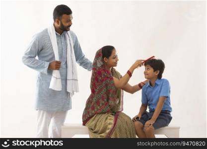 PORTRAIT OF A RURAL MOTHER GETTING SON READY WITH FATHER STANDING BESIDES