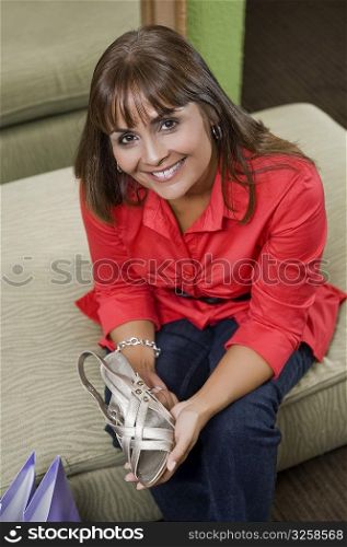 Portrait of a sales clerk holding a sandal and smiling