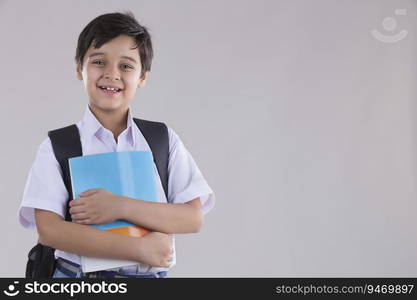 portrait of a school boy smiling with bag and books in hand 