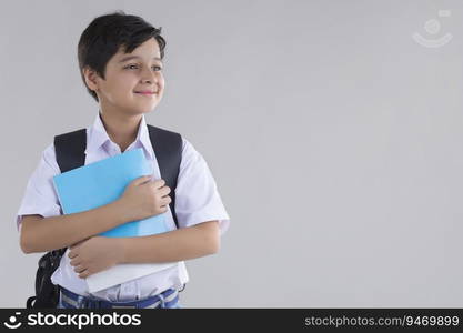 portrait of a school boy smiling with bag and books in hand 