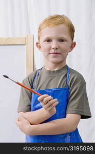 Portrait of a schoolboy holding a paintbrush and smiling