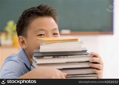 Portrait of a schoolboy holding a stack of books