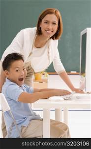 Portrait of a schoolboy with his female teacher in front of a computer