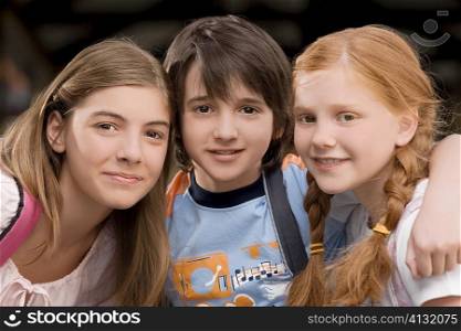 Portrait of a schoolboy with two schoolgirls smiling together