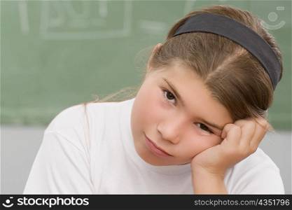 Portrait of a schoolgirl thinking in a classroom