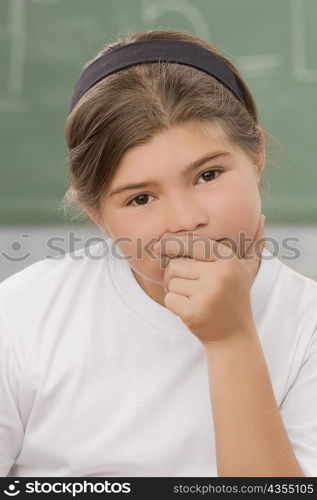 Portrait of a schoolgirl thinking in a classroom