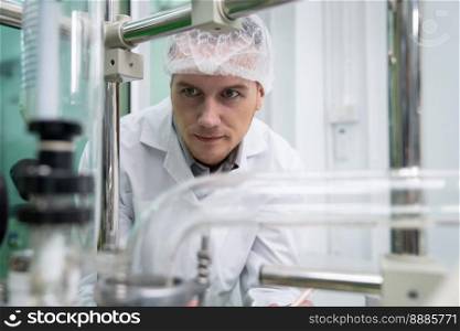 Portrait of a scientist, apothecary extracting cannabis oil with a glass tube for liquid flow in a laboratory. Cannabis extraction for alternative medical treatment concept.. Portrait of a scientist, apothecary extracting cannabis oil in laboratory.