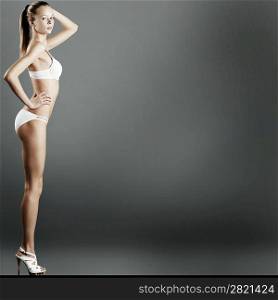 Portrait of a seductive female model in bikini posing against grey background