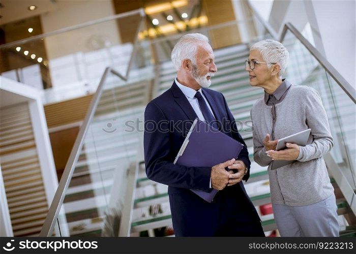 Portrait of a senior businessman  holding documents and businesswoman holding tablet computer were discussing jobs in modern office