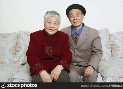 Portrait of a senior couple sitting on a couch smiling