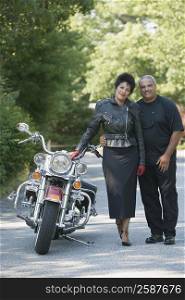 Portrait of a senior man and a mature woman standing beside a motorcycle