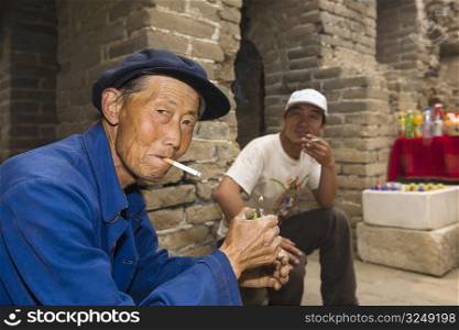 Portrait of a senior man and a mid adult man smoking, Great Wall Of China, Beijing, China